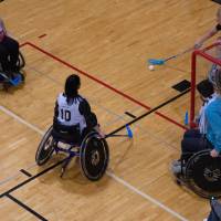 Adult hockey players in wheelchairs attempting to shoot on the net.